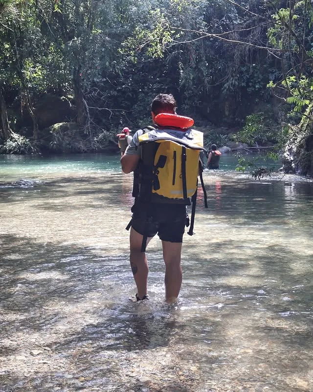 Vadeando el río en el Cañón del Río Claro con mochila estanca y remo